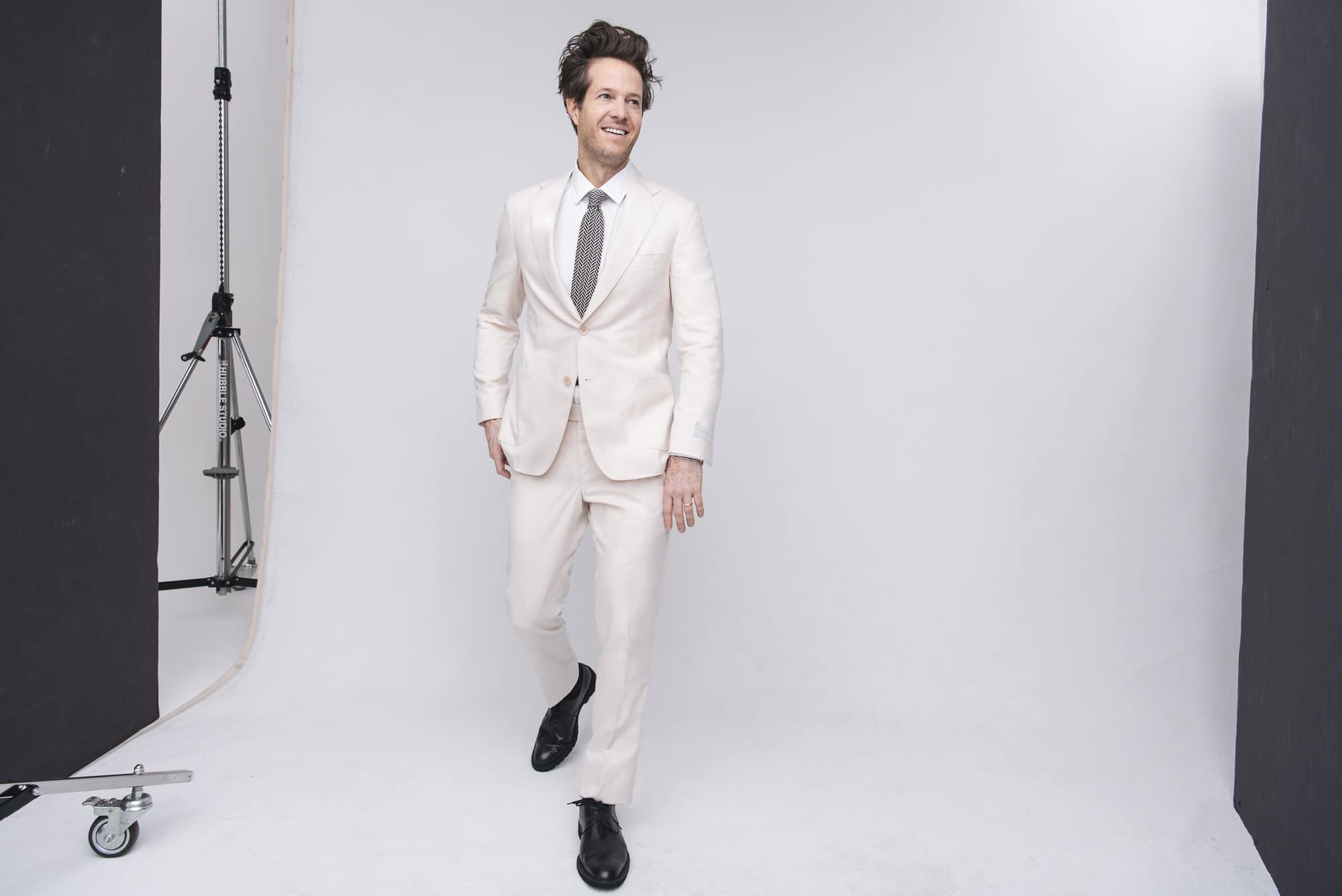 Oli wears ivory suit, white shirt by SAMUELSOHN. Shoes by GEORGE ESQUIVEL. Tie, stylist’s own.