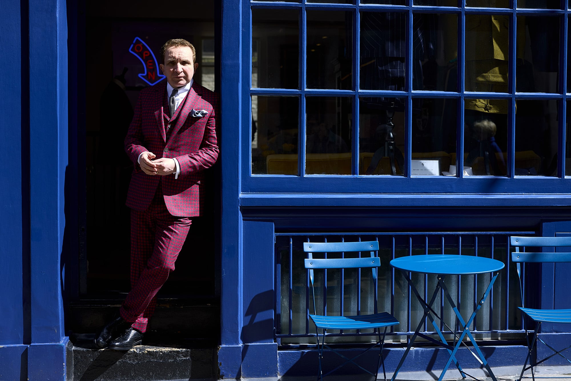 Eddie wears suit shirt, tie, and pocket square by Mark Powell. Shoes by Grenson. Glasses by Gentle Monster.